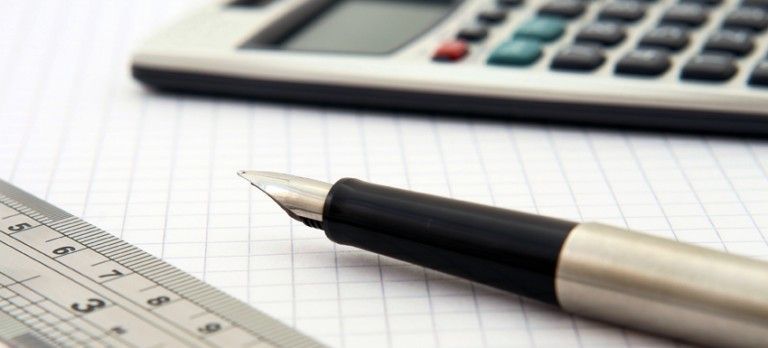 Calculator, pencil, and ruler on graph paper in an office setting