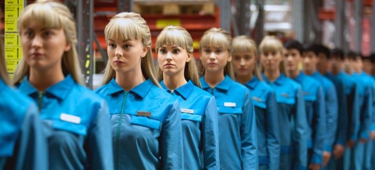 Row of workers in blue uniforms standing in a factory or assembly line corridor