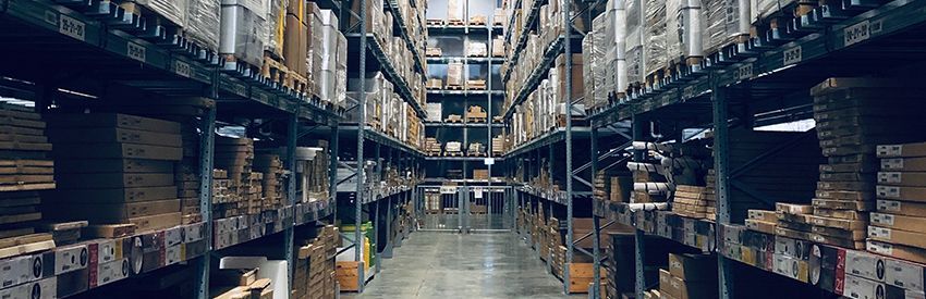 A large warehouse aisle with tall shelves stacked with boxes and supplies.