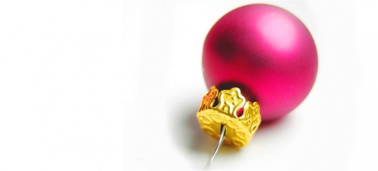 Pink Christmas ornament with gold cap on a white background