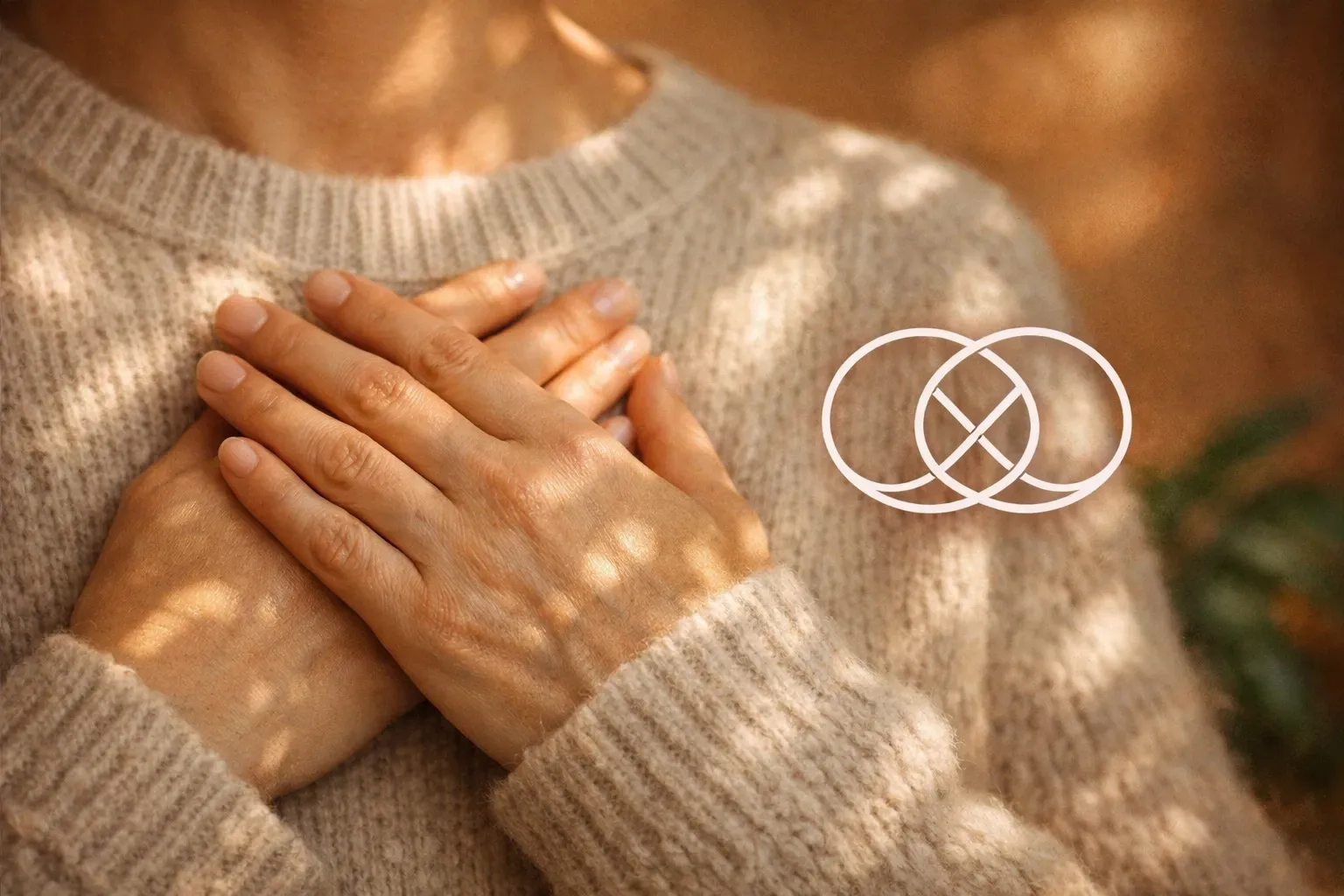 Person with hands on chest, wearing a beige sweater, with a white interconnected circle symbol.