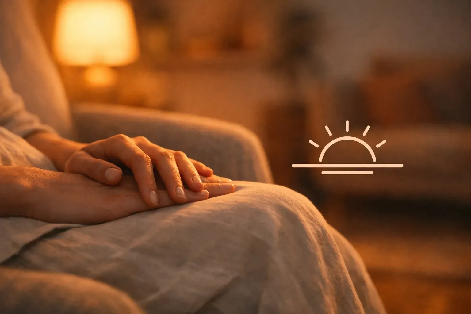 Hands resting on a lap in a warm, softly lit room, with a sunset icon overlaid on the right side.