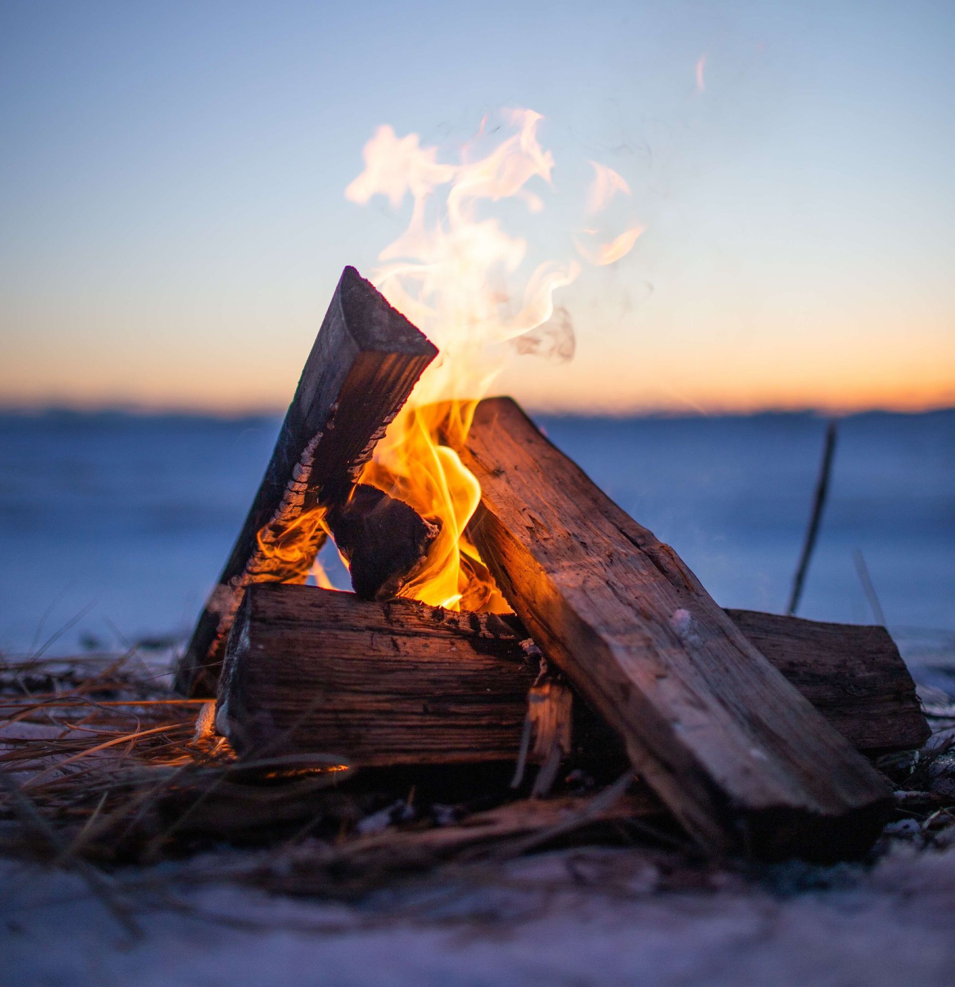 Campfire with flames against a snowy background at sunset. 4 lessons to learn from fire.
