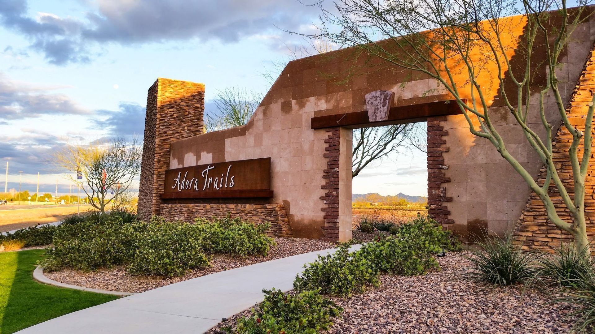A stone wall with a sign on it and a walkway leading to it.