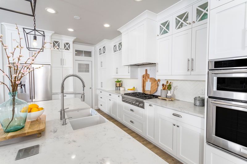 A kitchen with white cabinets , stainless steel appliances , a sink , and a stove.