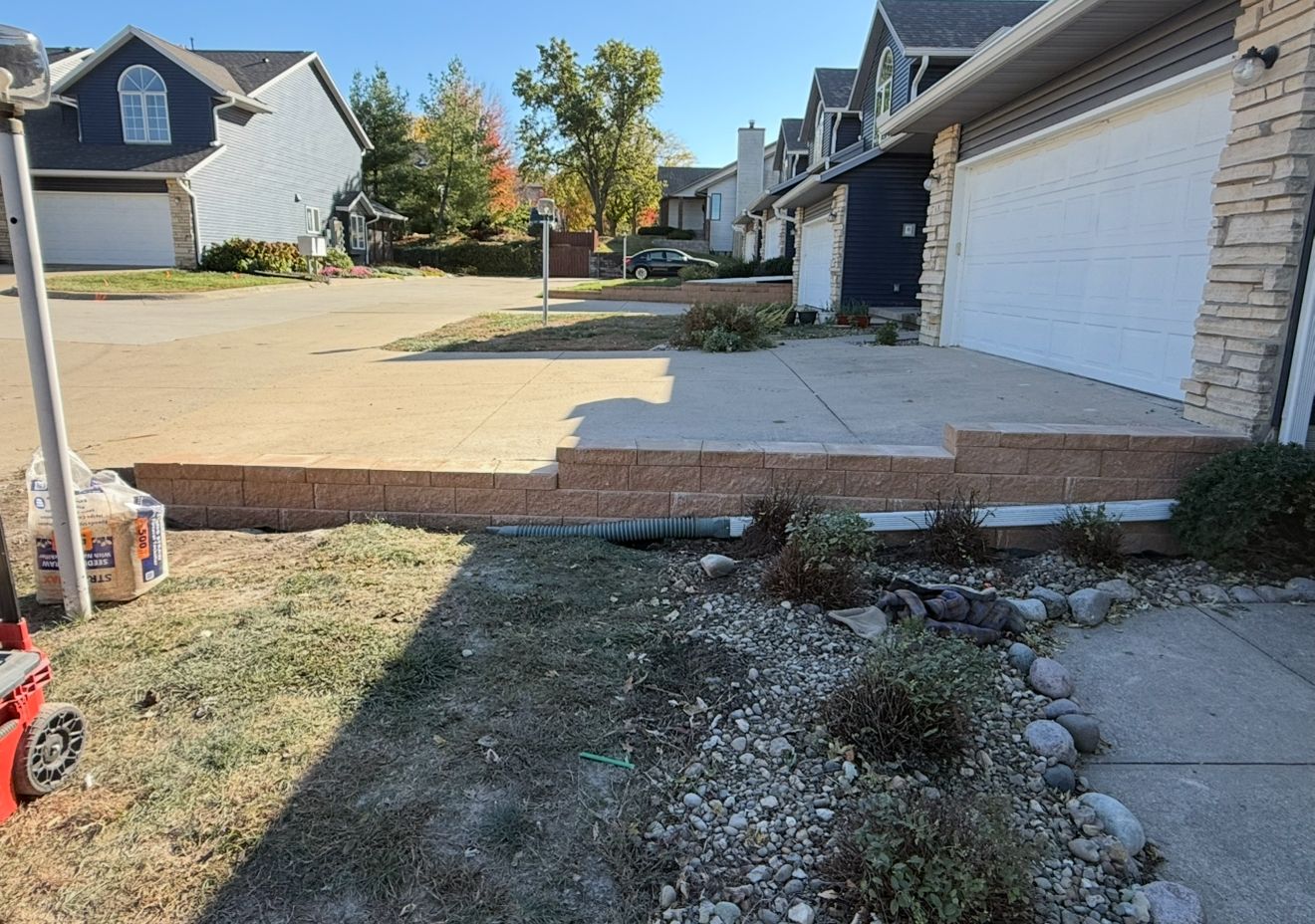 Suburban driveway and garage with a muddy, uneven patch of ground in the foreground