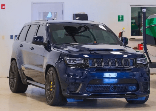 Dark blue Jeep Grand Cherokee SUV parked inside, with yellow brake calipers.