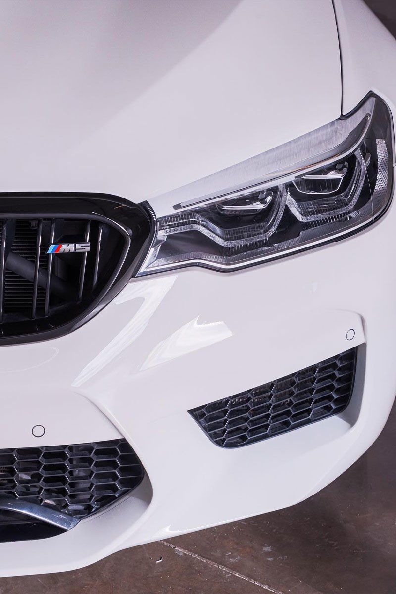 White BMW M5 front end with black grille and headlights.