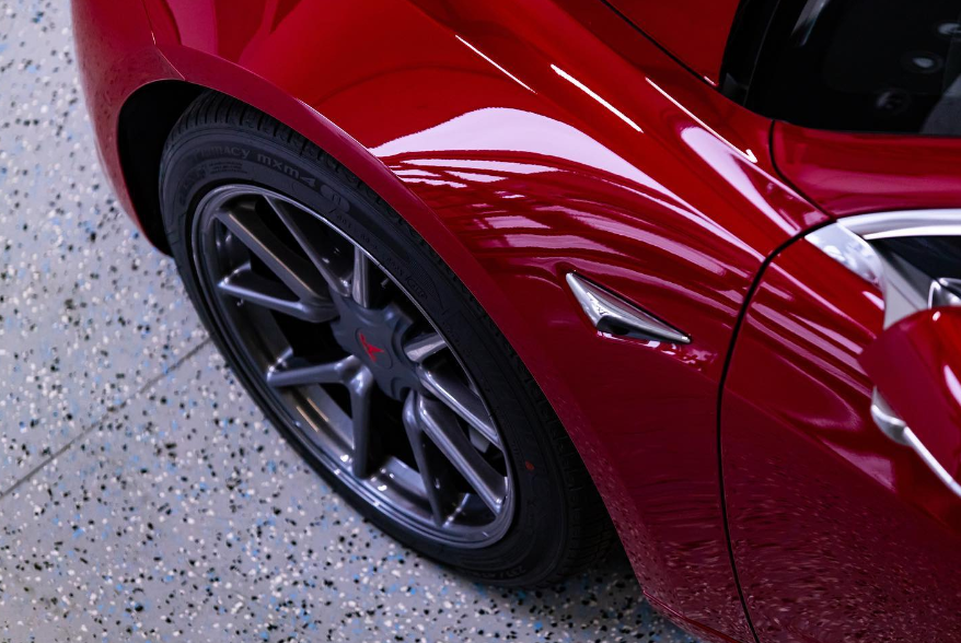 Red Tesla car front wheel and fender.