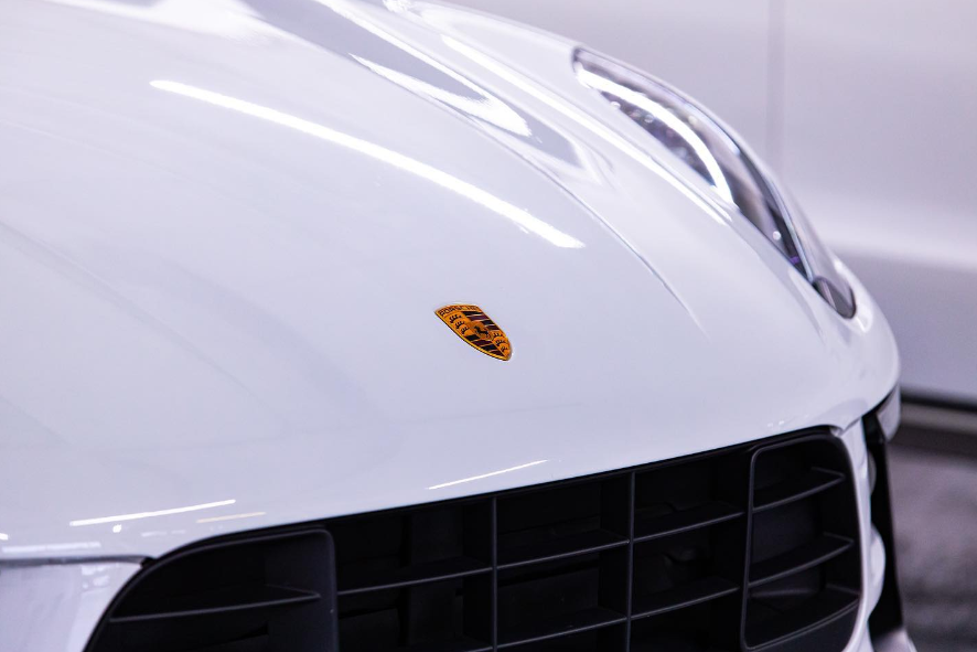 White Porsche car hood with the brand's emblem centered.