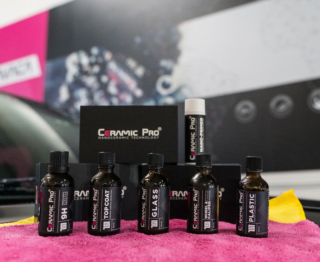Ceramic Pro car detailing products, including bottles and boxes, on a pink towel.
