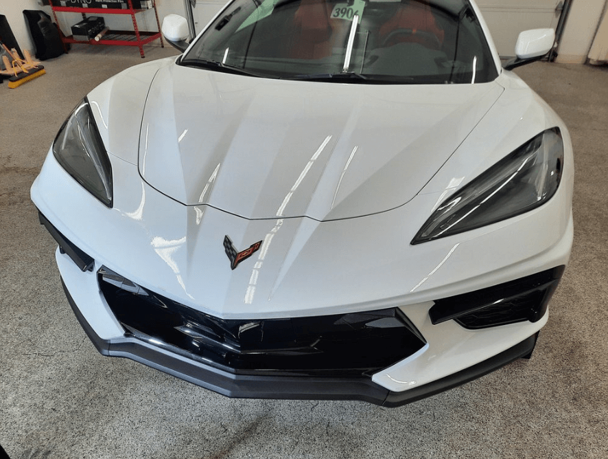 White Chevrolet Corvette sports car with black accents, parked indoors.