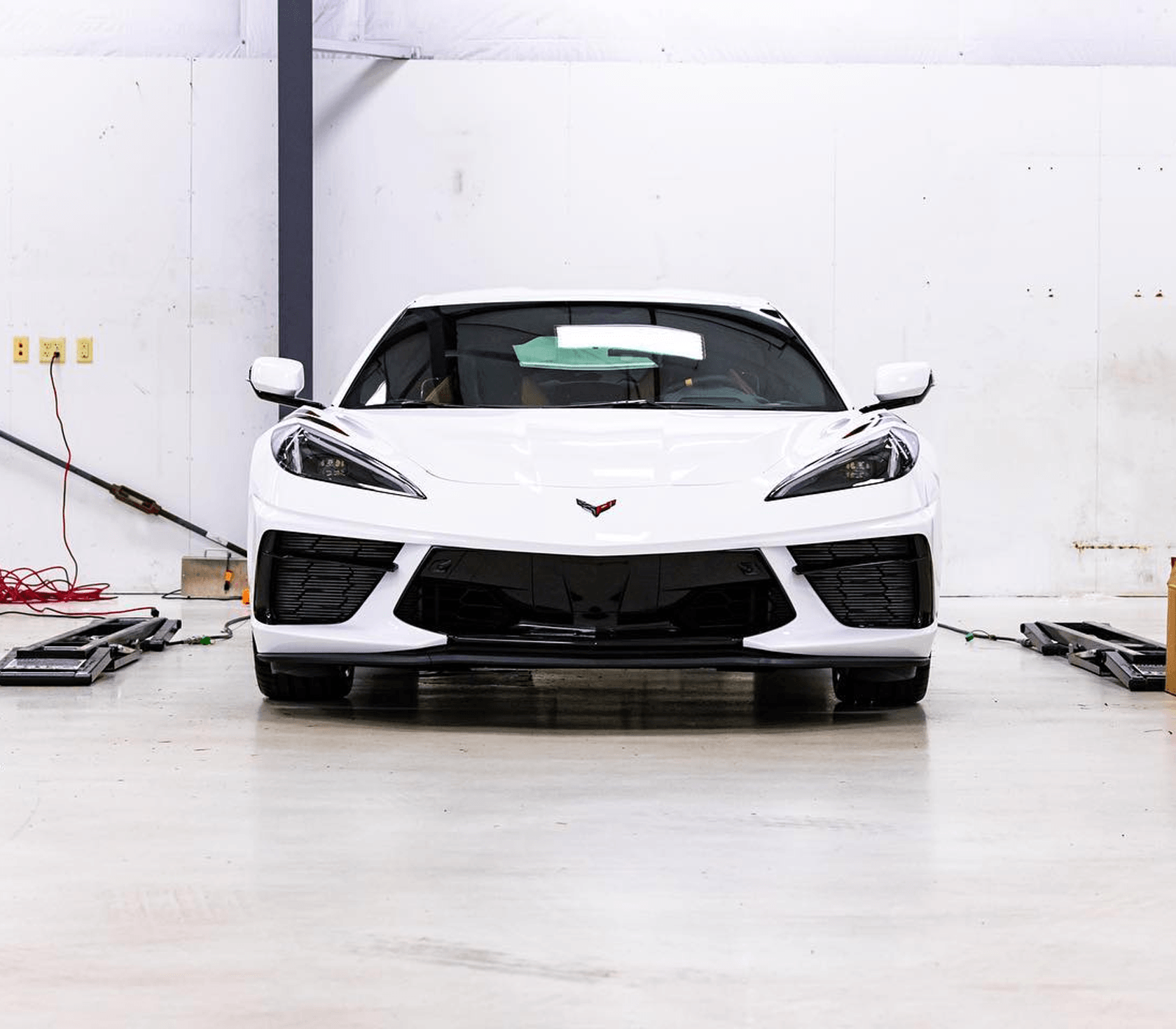 White Corvette sports car in a garage, straight-on view.