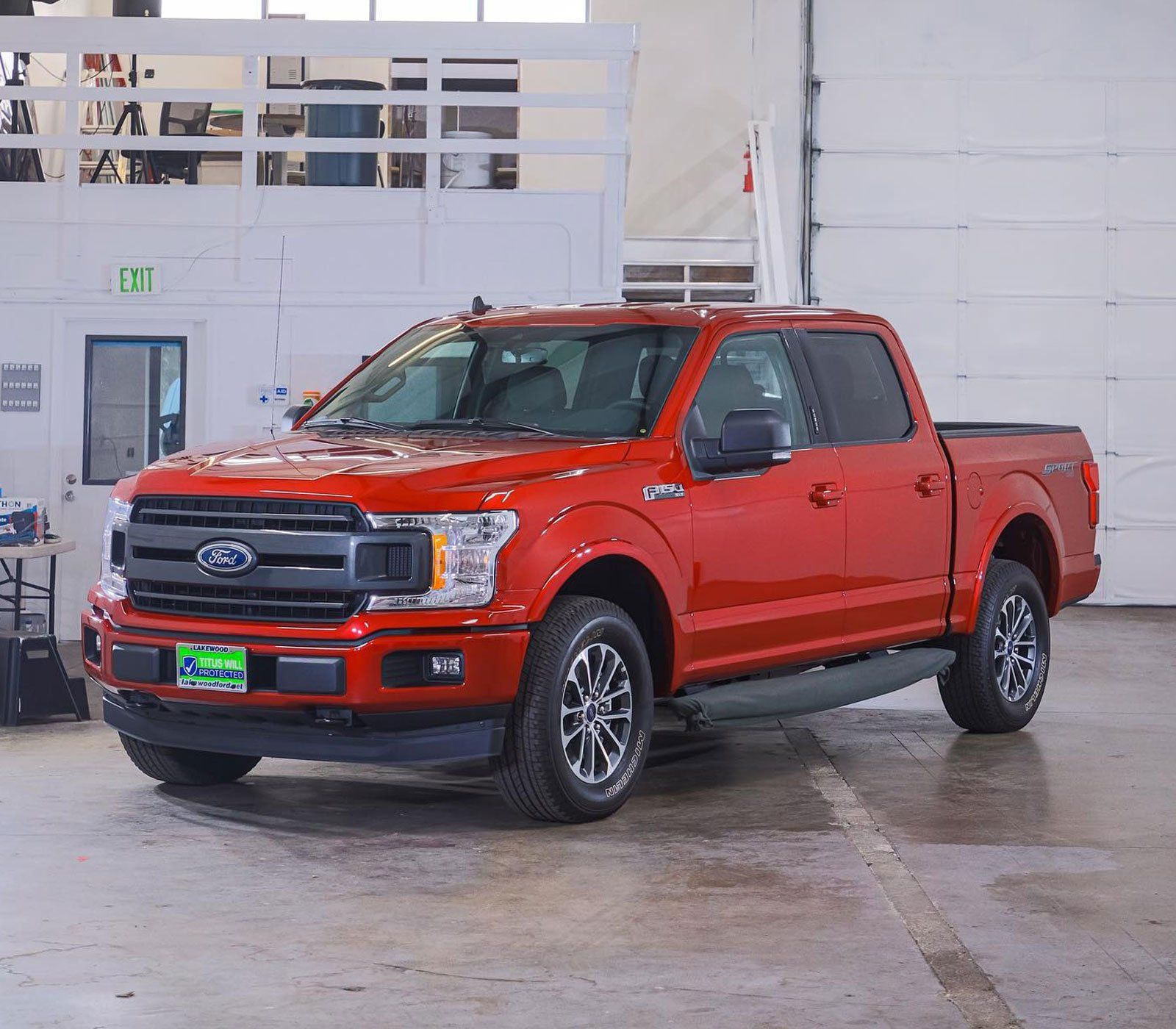 Red Ford F-150 pickup truck parked inside a building with white walls and a concrete floor.