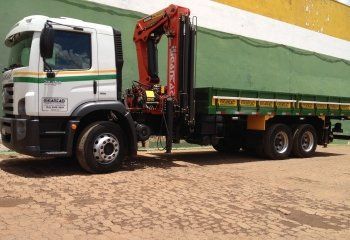 Um caminhão branco com um guindaste vermelho na traseira está estacionado em um estacionamento