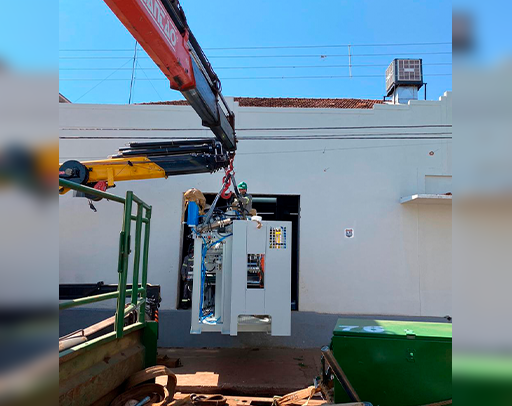 Um guindaste está levantando uma máquina para dentro de um prédio.