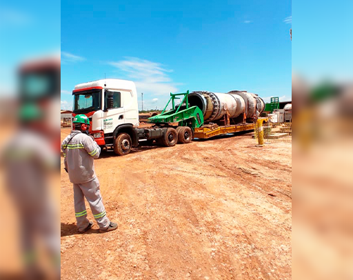 Um homem está parado na frente de um caminhão que transporta um objeto grande.