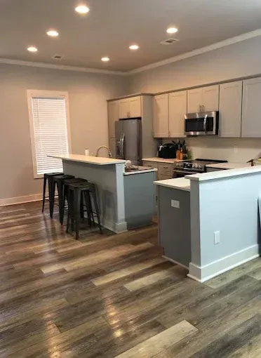 A kitchen with stainless steel appliances and wooden floors.