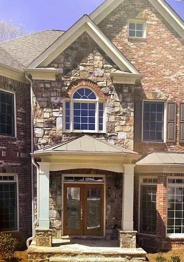 A large brick and stone house with a porch and stairs
