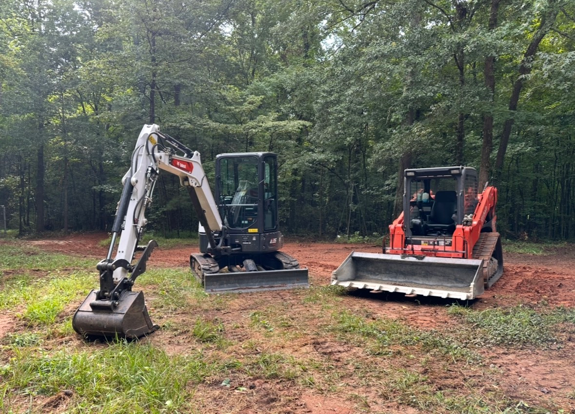 Two bulldozers are parked next to each other in a dirt field.