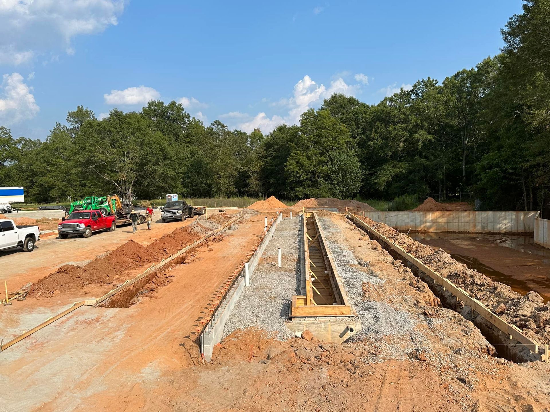 A construction site with a lot of dirt and trees in the background.