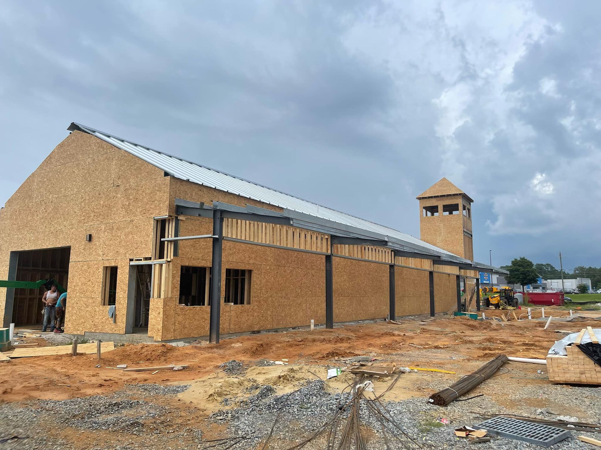 A large wooden building is being built in a dirt field.