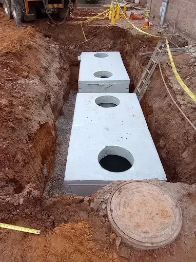 A concrete septic tank is being installed in a hole in the ground.