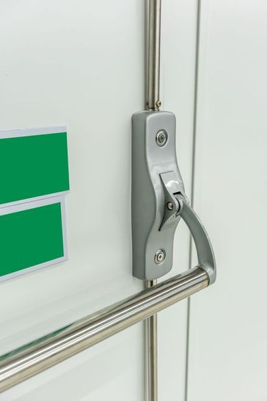 Primo piano di un chiavistello metallico su una porta bianca con un cartello verde e una barra orizzontale.