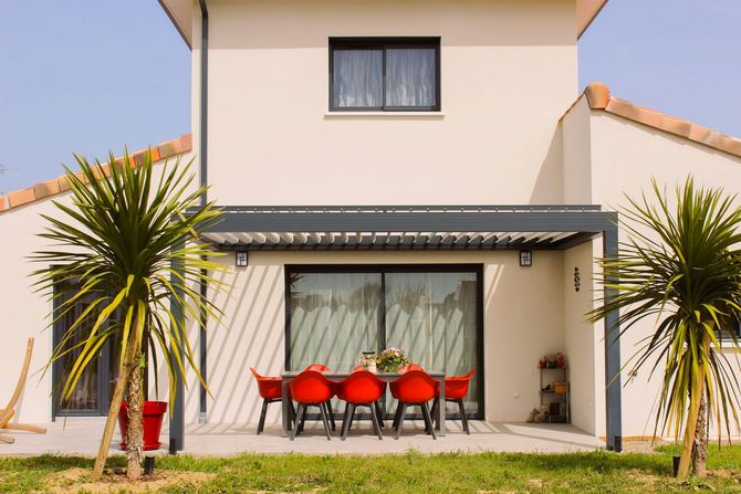 Modern two-story house with patio, red chairs, and palm trees in front yard