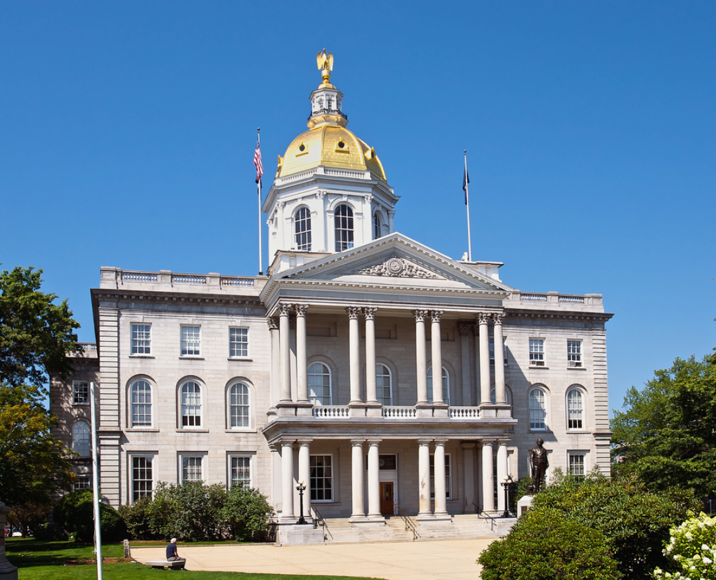 Historic white courthouse with golden dome and columns under a clear blue sky