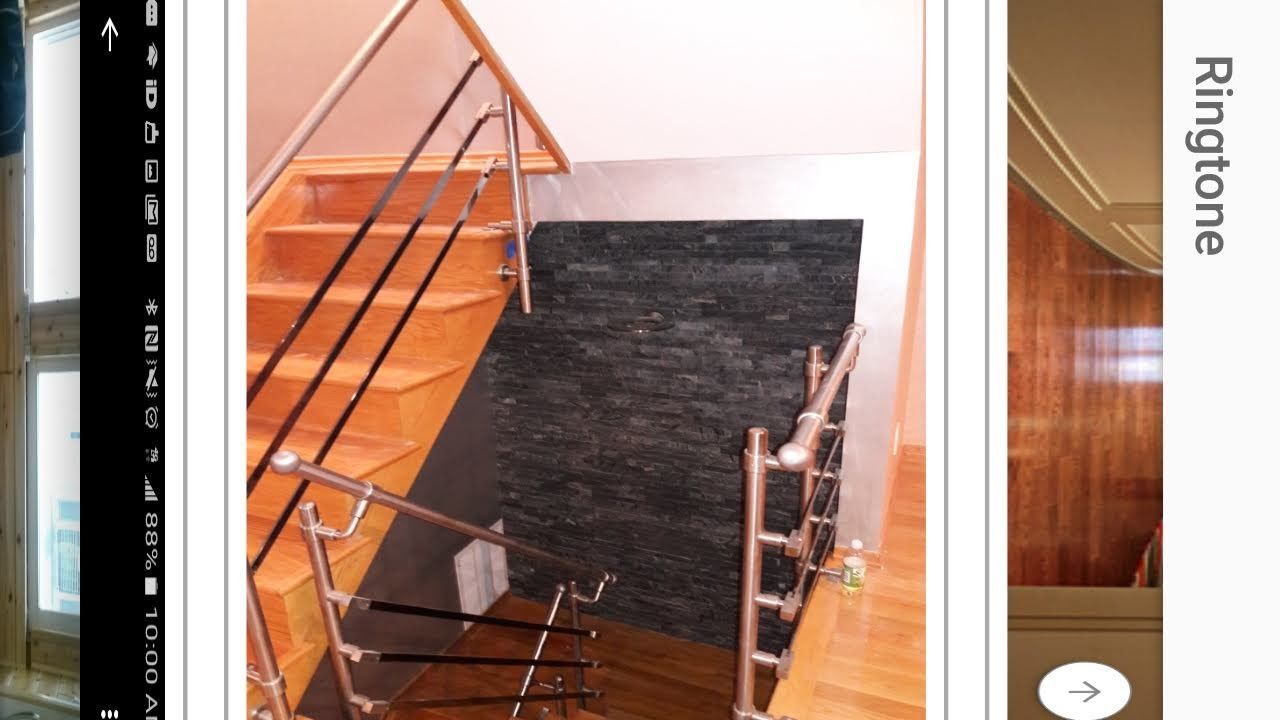 A staircase with metal railings and a dark, textured stone wall accent in a home interior.