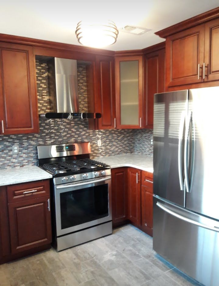 A modern kitchen featuring rich cherry-stained wood cabinets, stainless steel appliances, and a tiled backsplash.
