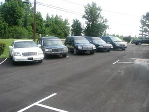 Five parked cars in a row along a roadside lot, with trees and power lines in the background