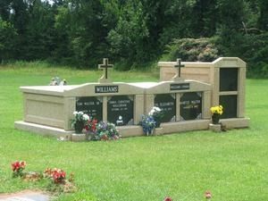 Small grave monument with flowers in a green cemetery setting