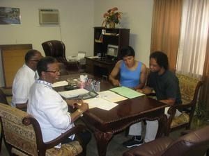 Four people sit around a dining table in a living room, reviewing papers and discussing.