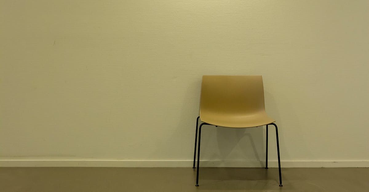 A wooden chair is sitting in front of a white wall.