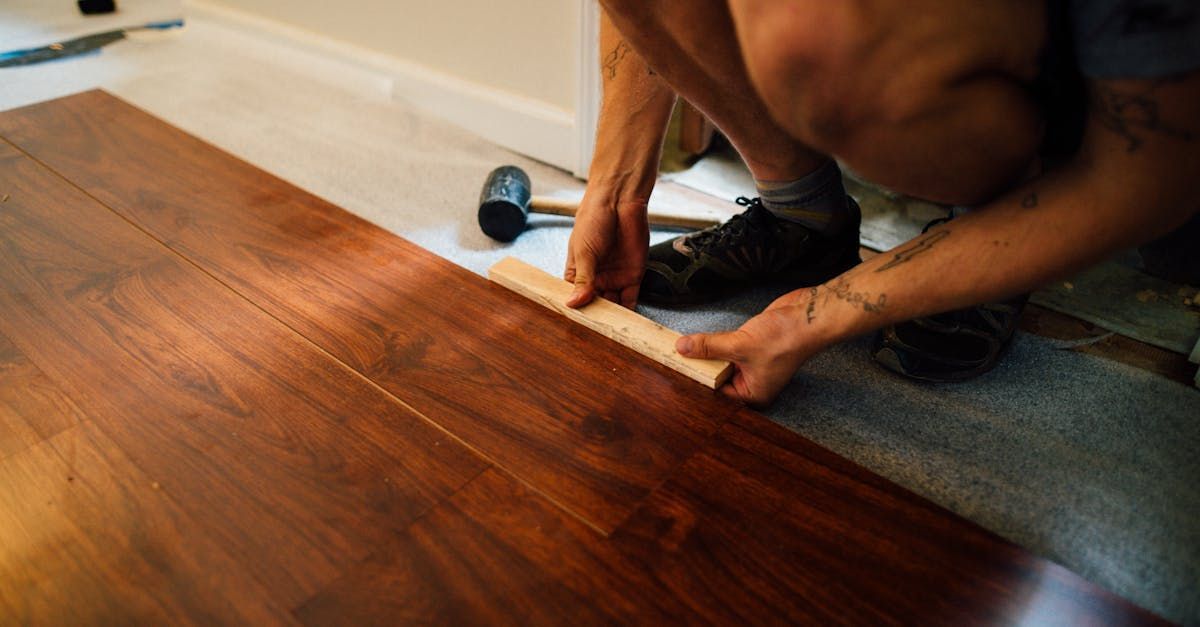 A man is installing a wooden floor with a hammer.