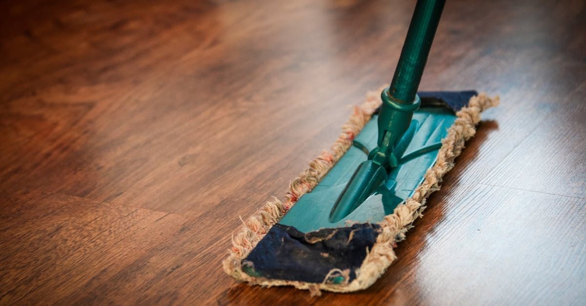 A person is mopping a wooden floor with a mop.