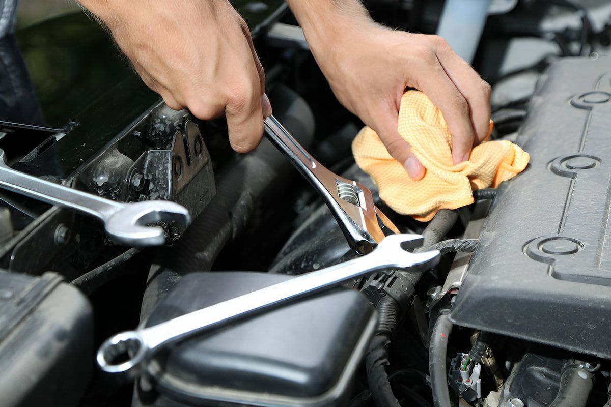 A Person Is Working On A Car With A Wrench And A Towel — Cameron Brothers Automotive In Currajong, QLD