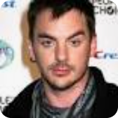 Man with dark hair and stubble, looking directly at the camera.