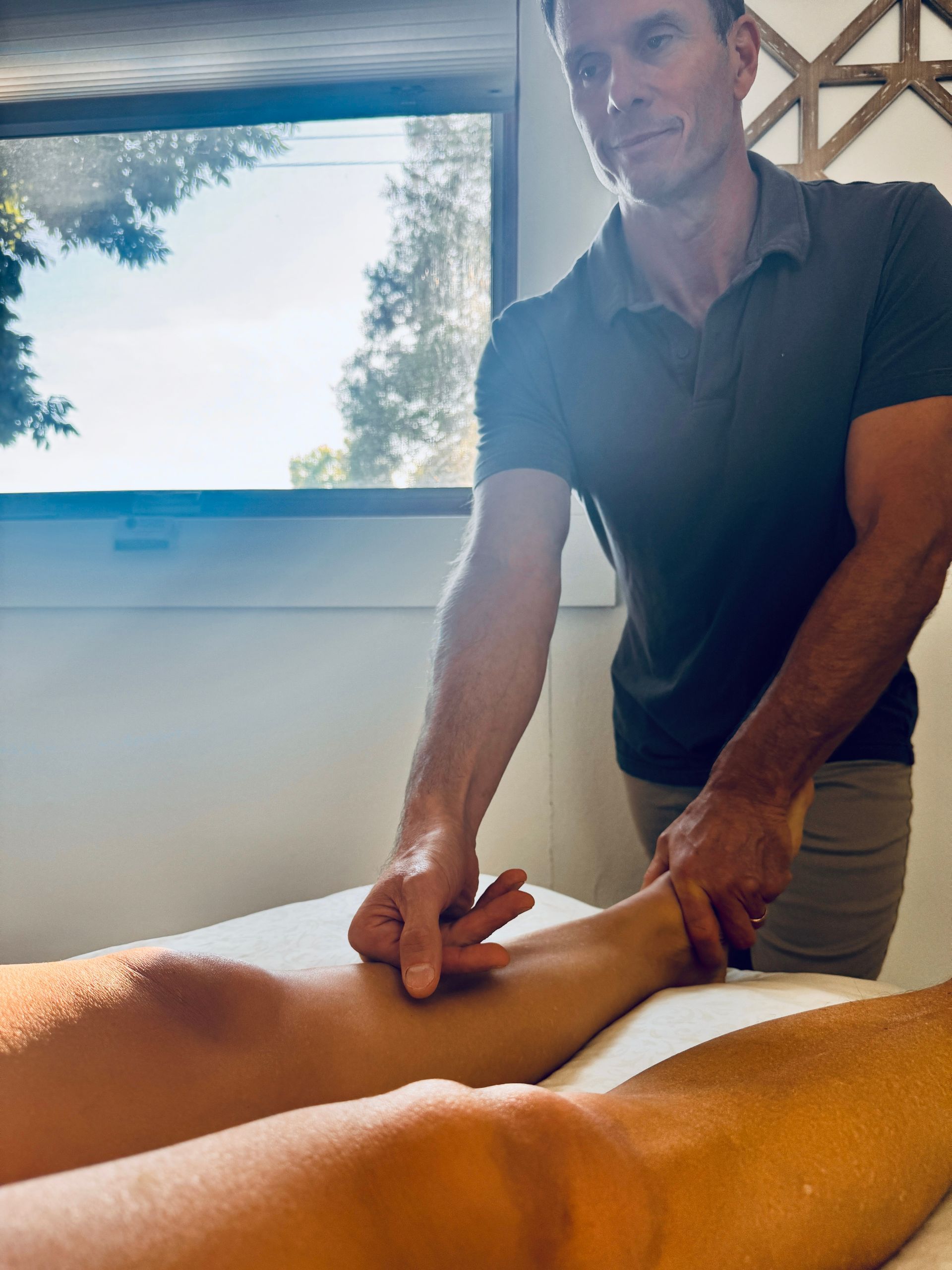 Man giving leg massage in a spa-like setting. The recipient is lying down.
