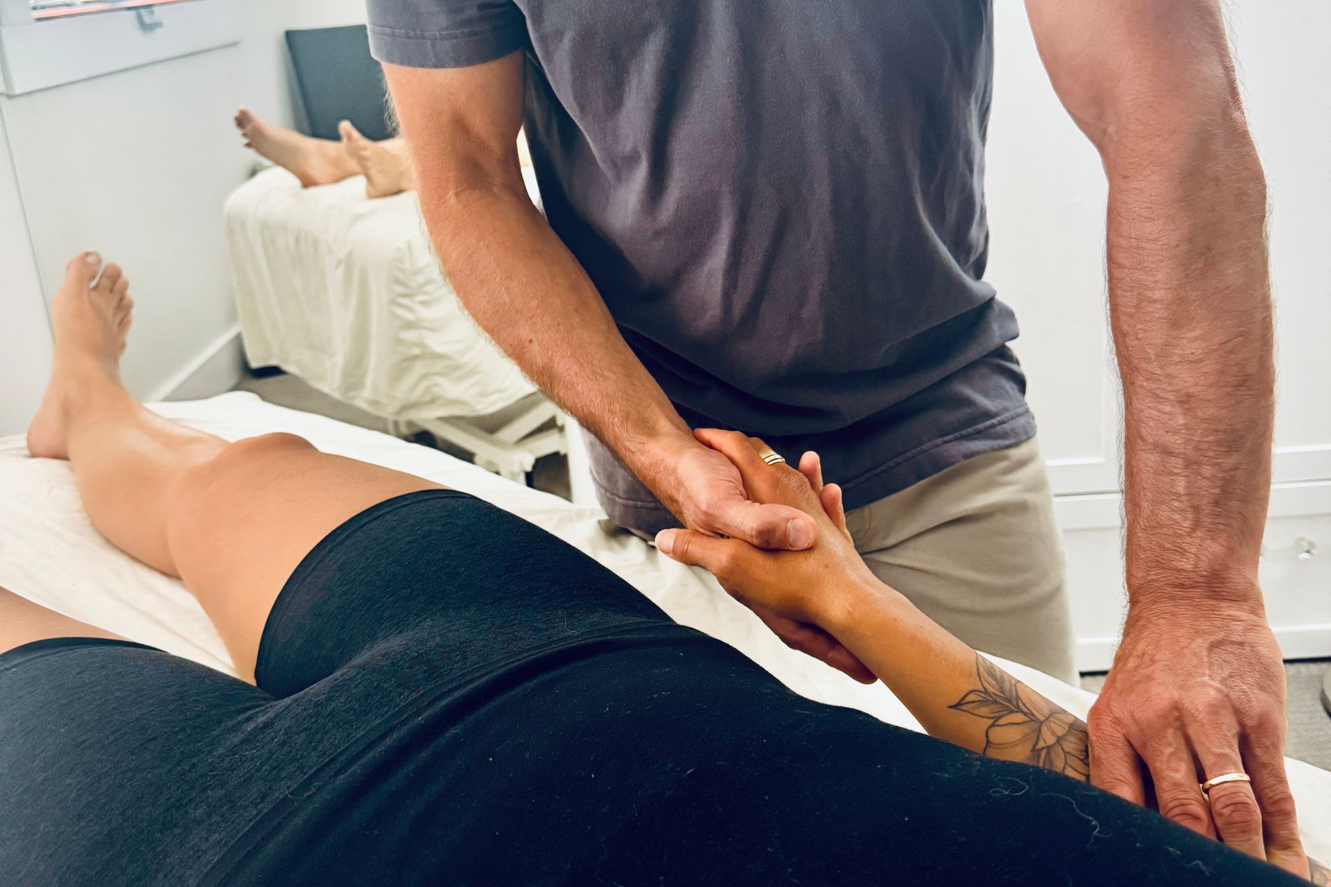 Man providing hand therapy to a person lying on a massage table. Therapy room.