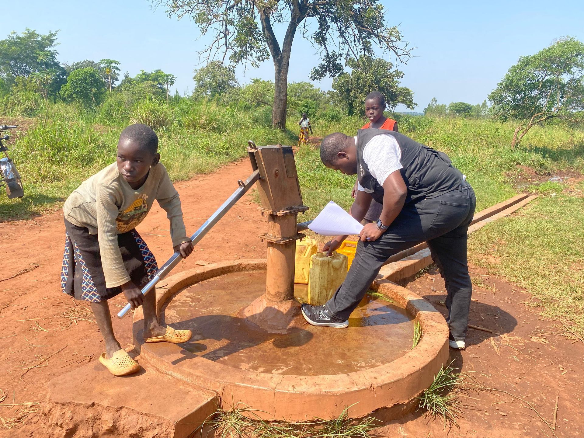 Korobar Village, Nwoya District, Uganda — the borehole in use with a child at the hand pump, June 2026.