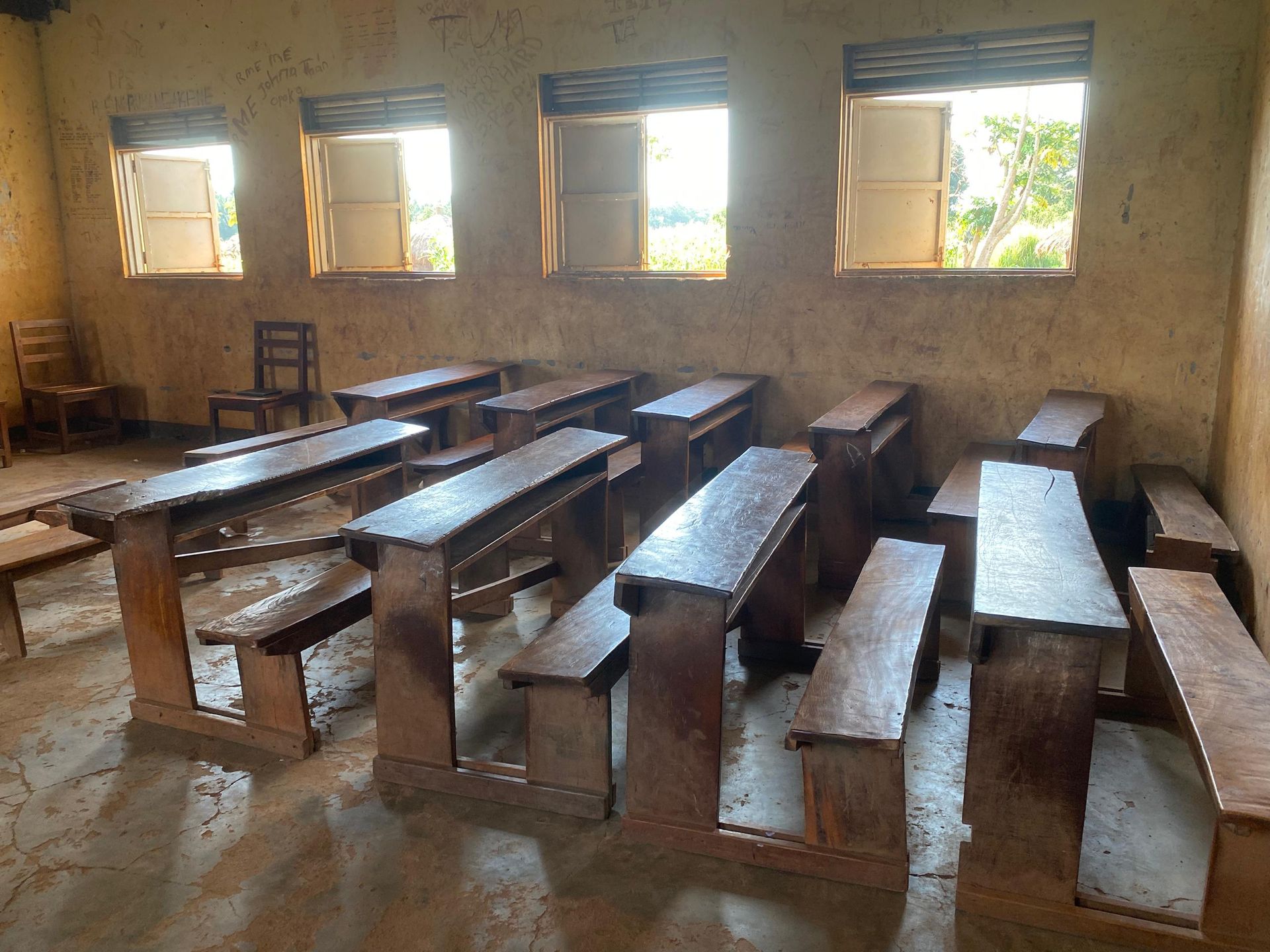 Orua Community Nursery and Primary School, Korobar Village, Nwoya District, Uganda — empty classroom with rough plank benches, June 2026.