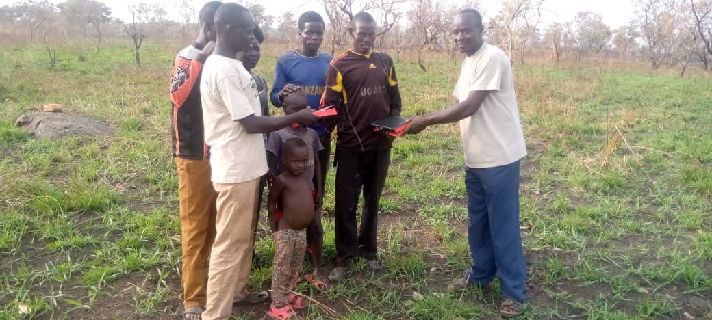 A group of men are standing in a grassy field holding hands.