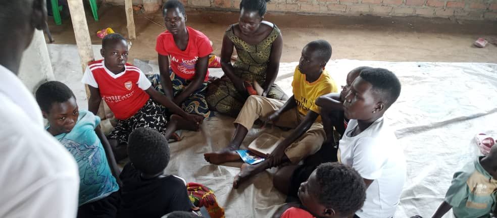 A group of people are sitting on the floor in a circle.