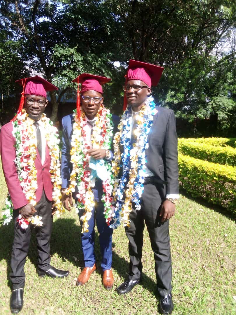 Three men in graduation caps and gowns are posing for a picture.