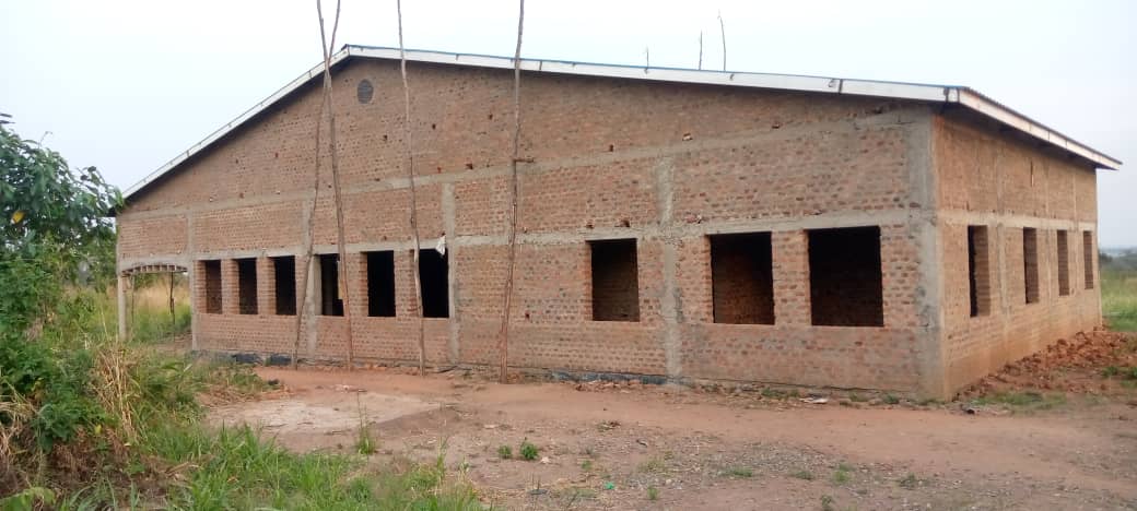 A brick building is being built in the middle of a field.