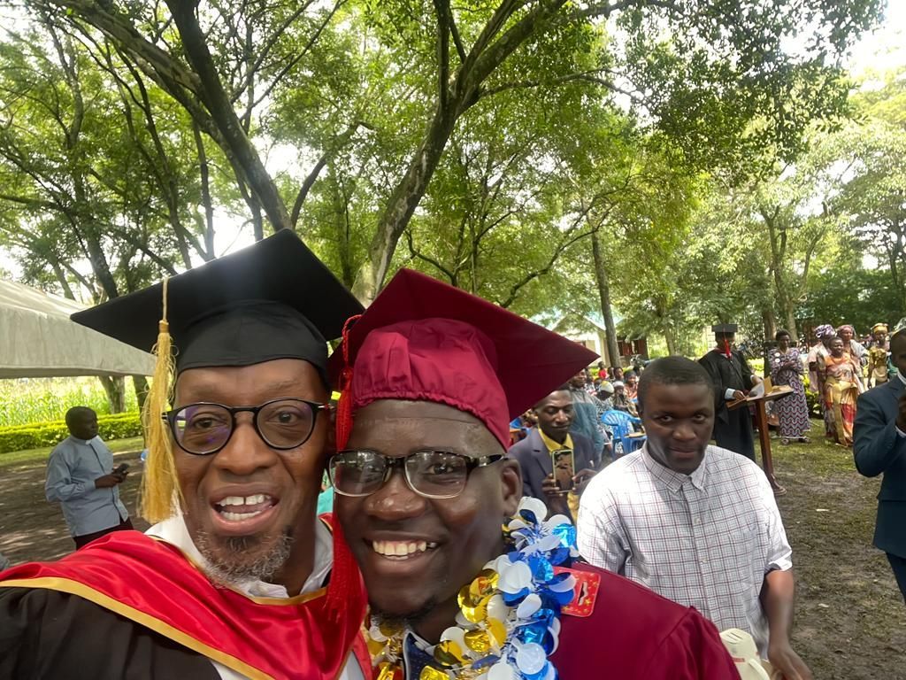 Two men in graduation caps and gowns are posing for a picture.
