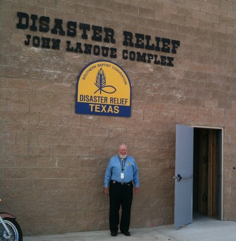 Man standing in front of Disaster Relief building. Sign on wall, open door.